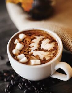 Delicious hot chocolate topped with marshmallows and latte art, perfect for cozy autumn days.