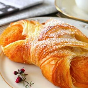 A delicious croissant filled with apricot on a decorative plate, perfect for breakfast delight.